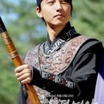 Young warrior in traditional Korean armor holding spear