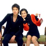 Young couple seated on bench, woman holding purse