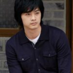Young man with dark hair wearing navy shirt
