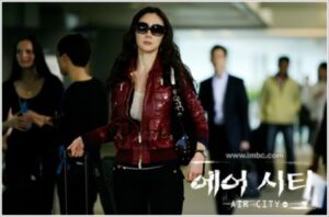Woman in red jacket with suitcase at airport