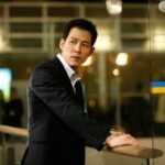 Man in suit leaning on glass railing