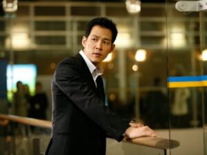 Man in suit leaning on glass railing