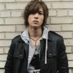 Young man wearing leather jacket by brick wall