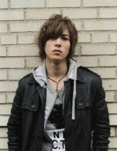 Young man wearing leather jacket by brick wall