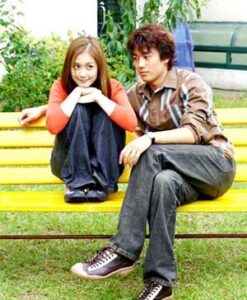 Two people sitting on yellow park bench