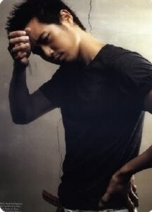 Moody portrait of young man touching forehead