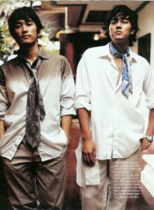 Two men standing indoors wearing loose neckties