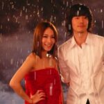 Couple standing in rain, woman in red dress