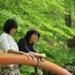 Couple leaning on orange railing in park