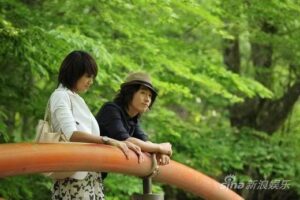 Couple leaning on orange railing in park