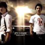 Two men with dramatic sky and city lights