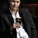 Man in suit holding pint of Guinness