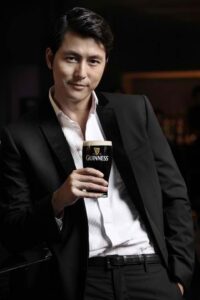 Man in suit holding pint of Guinness