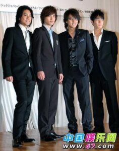 Four men in black suits posing together