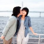 Young couple by waterfront, man kissing woman's cheek