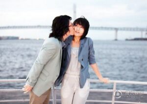 Young couple by waterfront, man kissing woman's cheek