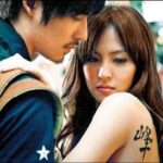 Man leans toward woman with shoulder tattoo