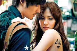 Man leans toward woman with shoulder tattoo