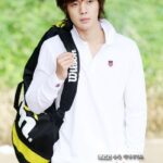 Young man carrying tennis bag in white outfit