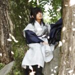 Person in traditional robe beneath falling cherry blossoms