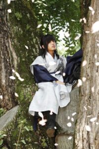 Person in traditional robe beneath falling cherry blossoms