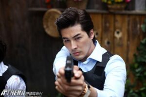 Man in vest pointing pistol at camera