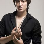 Young man in black shirt posing with necklaces