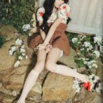 Young woman sitting on rocks among flowers