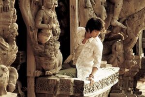 Seated person in white shirt amid intricate carvings