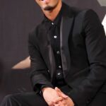 Smiling person seated in black suit