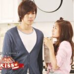Woman offering drink to serious man in kitchen