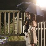 Young couple under umbrella on nighttime bridge
