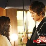 Young couple sharing umbrella at night
