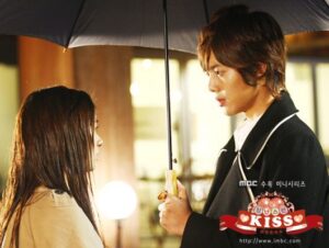 Young couple sharing umbrella at night