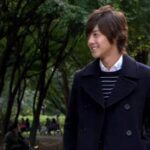 Smiling man walking through tree-lined park