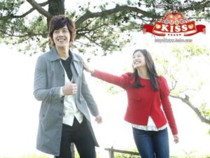 Two smiling people walking outdoors under a tree