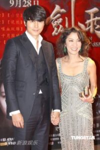 Well-dressed couple holding hands on red carpet