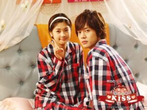 Two young people wearing matching red plaid pajamas