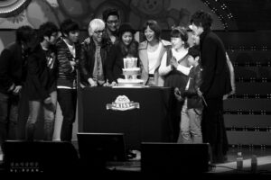 Group celebrating birthday with cake on stage