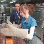 Woman wearing oven mitts handling freshly baked loaves