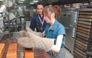 Woman wearing oven mitts handling freshly baked loaves