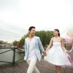 Smiling couple holding balloons walking on bridge