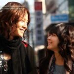 Two smiling women walking on sunny city street