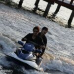 Two people on blue jet ski near pier