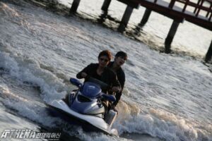Two people on blue jet ski near pier