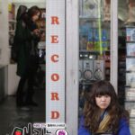 Young woman seated outside record store window