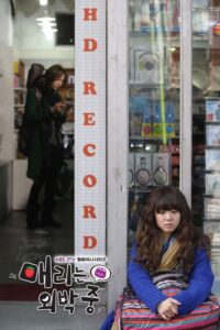 Young woman seated outside record store window