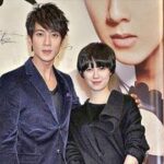 Two people posing in front of poster