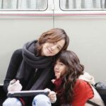 Two women leaning together by camper van
