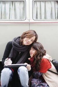 Two women leaning together by camper van